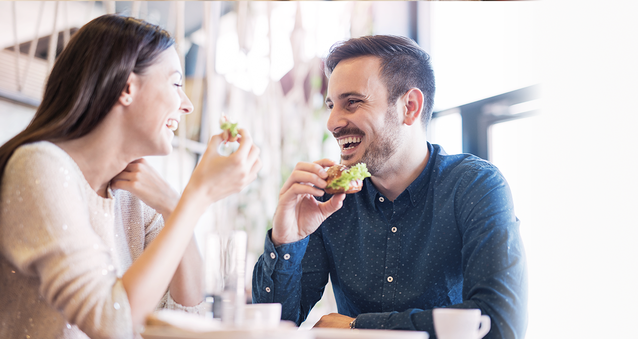 Lachende Frau und Mann im Restaurant mit belegten Brötchen