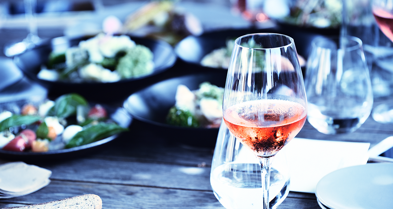 Glas mit Roséwein auf einem Tisch mit Salaten
