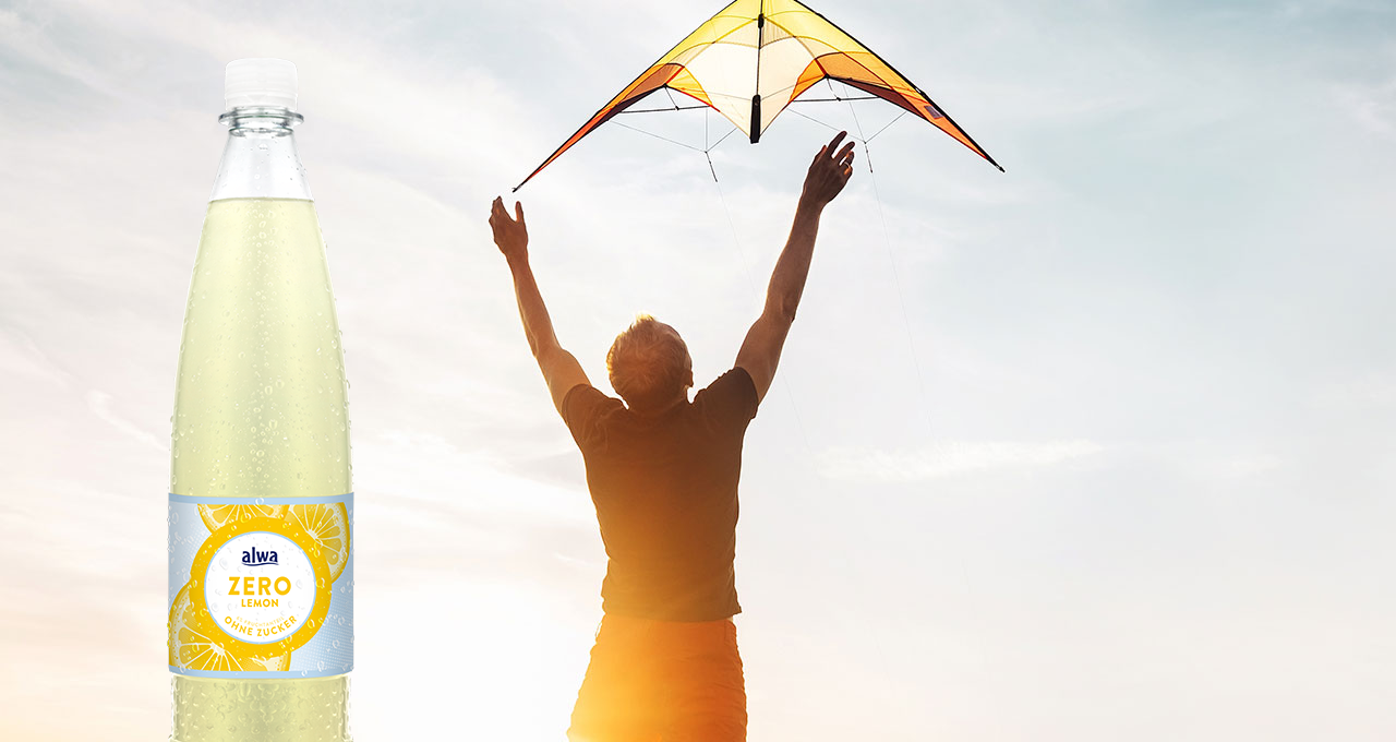 Mann mit Lenkdrache und Zitronenlimonade ohne Zucker in der Flasche