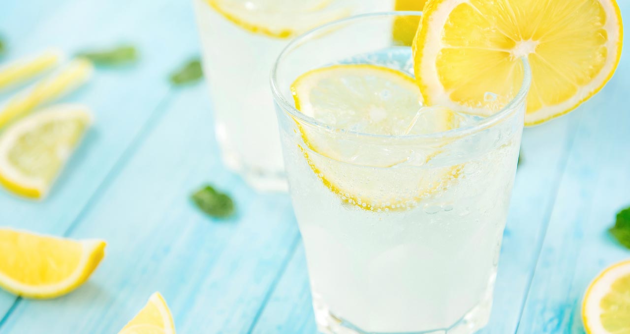 Zitronenlimonade im Glas mit Eiswürfeln und Zitronenscheiben