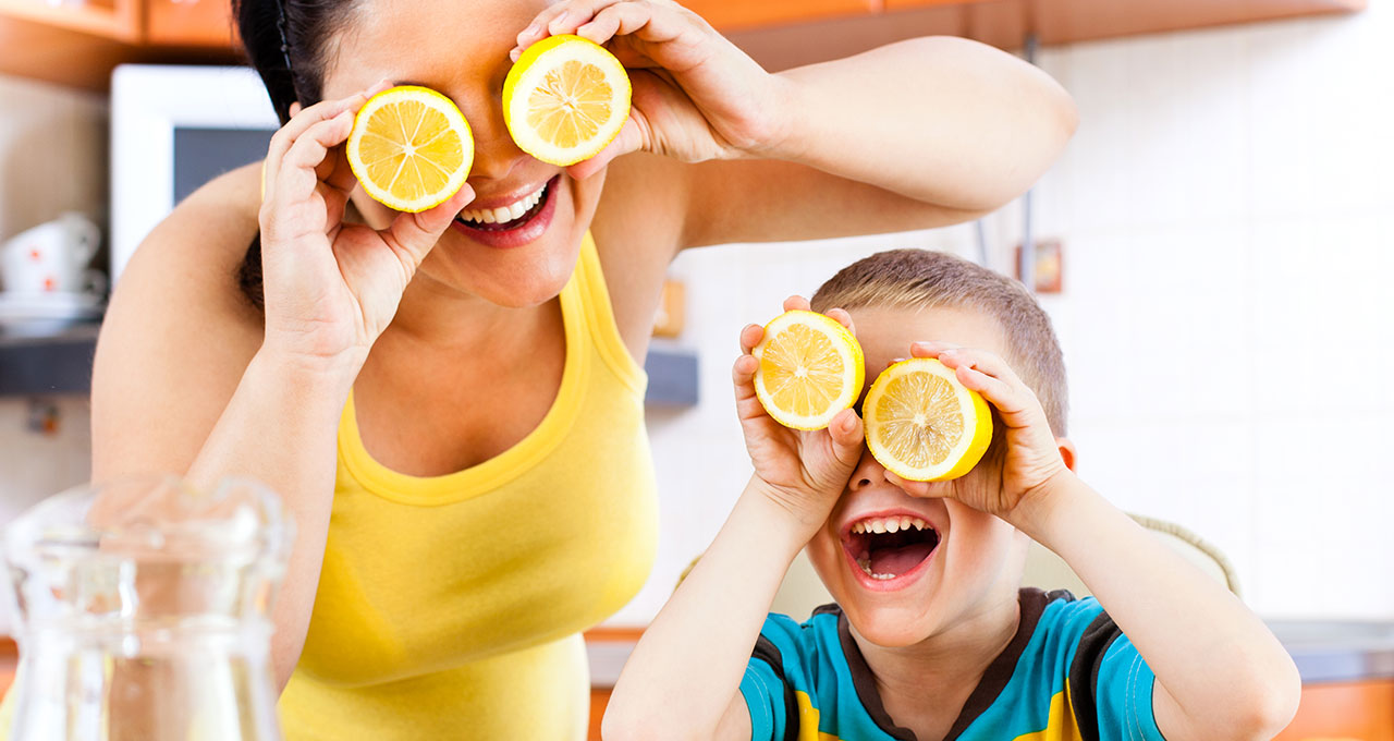 Frau und Kind halten sich Zitronenscheiben vor die Augen