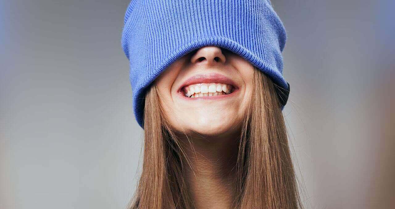 Lächelnde Frau mit weißen Zähnen und Mütze