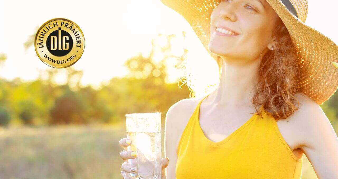 Frau mit Sonnenhut und Mineralwasserglas