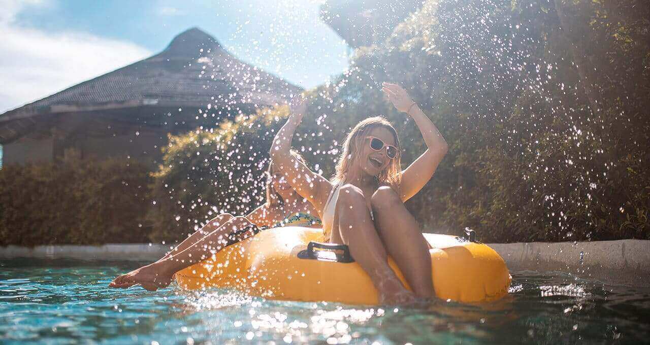 Frauen auf gelben Schwimmringen im Pool