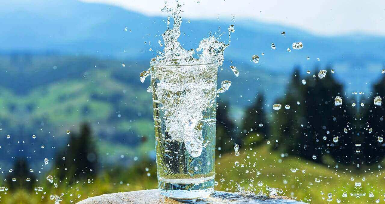 Mineralwasser spritzt aus Glas