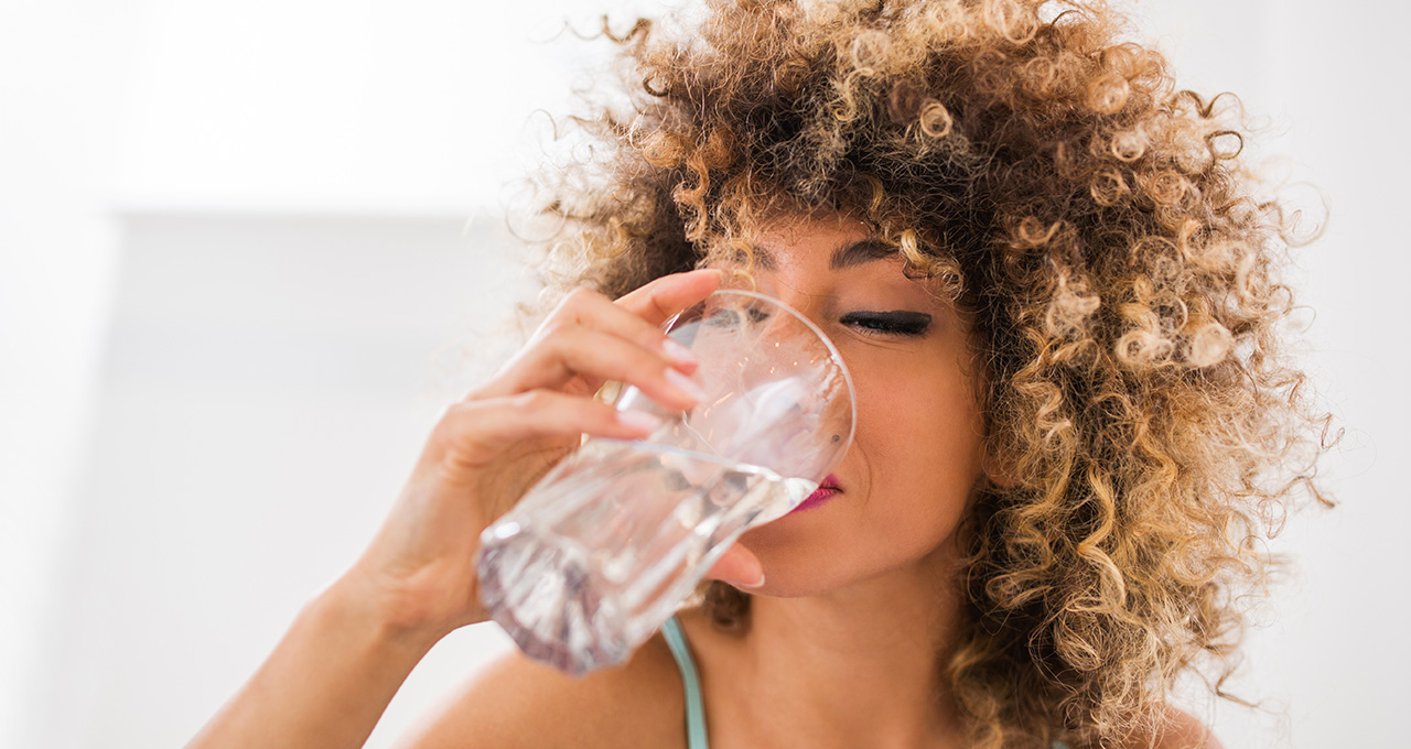 Frau trinkt aus Glas mit Mineralwasser medium