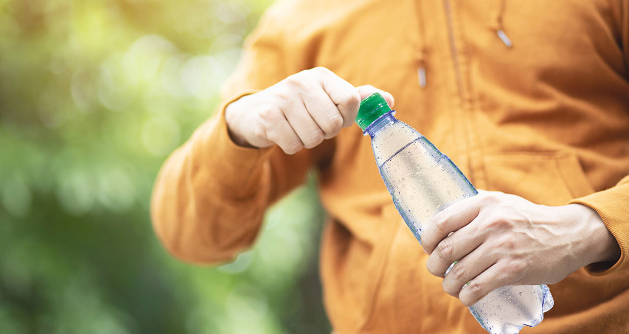 Person dreht Mineralwasser medium Flasche auf