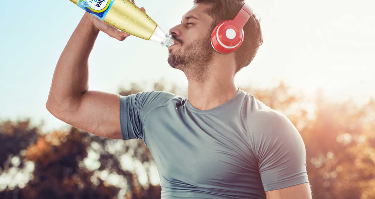 Mann mit Kopfhörern trinkt das Sportgetränk Apfel aus der Flasche