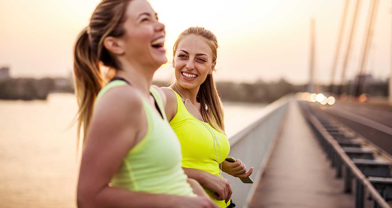 Sportliche Frauen stehen lachend auf einer Brücke