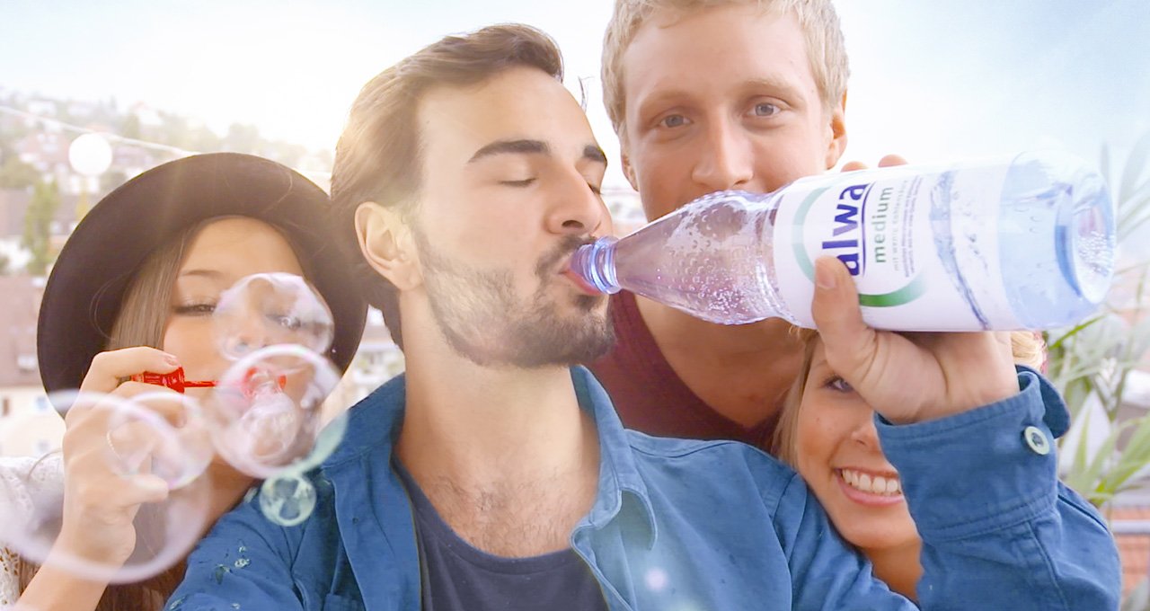 Junge Erwachsene trinken aus Mineralwasserflasche