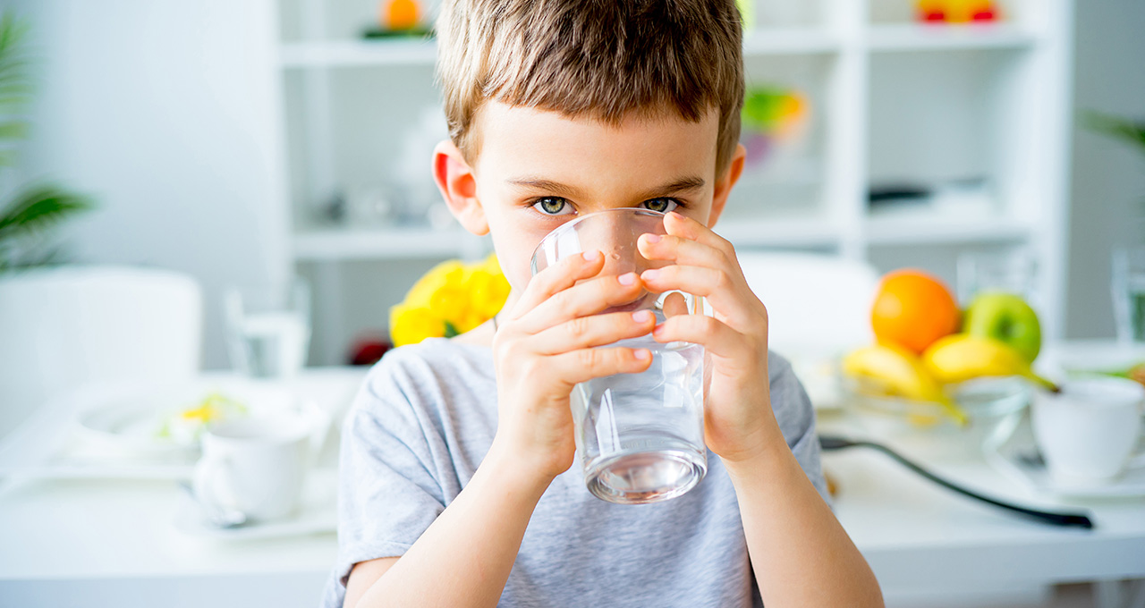 Junge trinkt aus Wasserglas