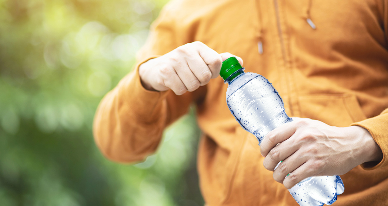Mensch mit Mineralwasserflasche in der Hand