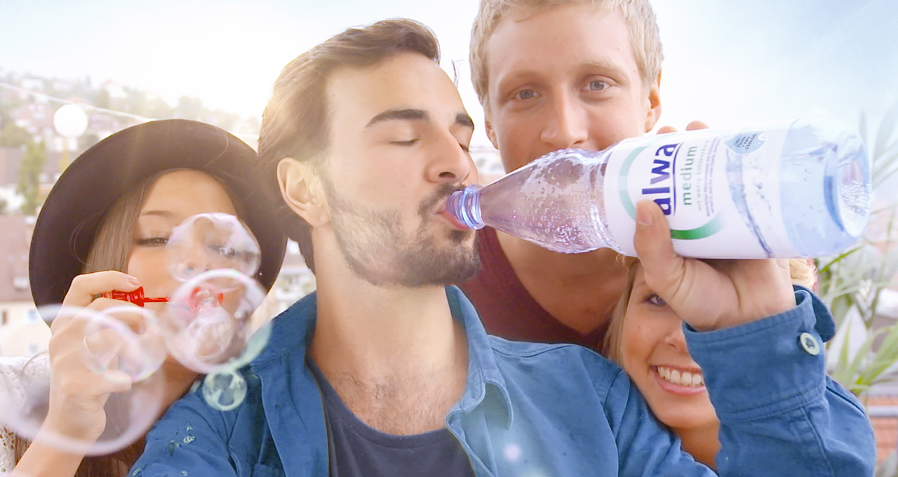 Junge Erwachsene trinken aus Mineralwasserflasche